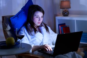 Attractive girl is spending time in front of her laptop at night