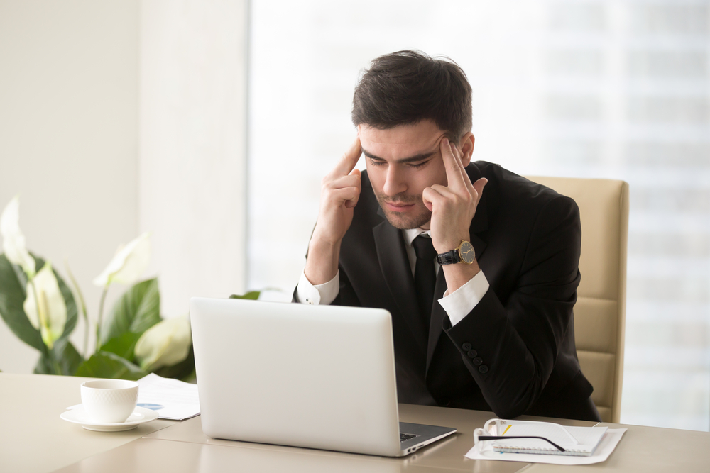 man in a suit sitting at a desk trying to concentrate